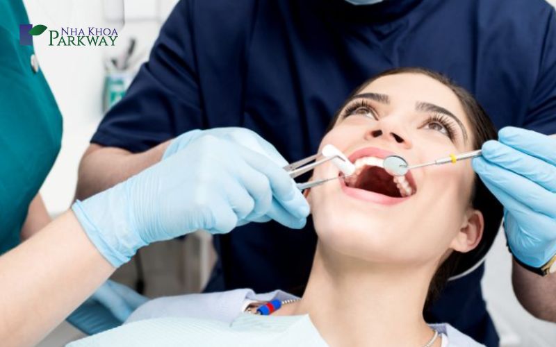 Nha sĩ kiểm tra răng của cô gái bằng gương và các loại dụng cụ y khoa
