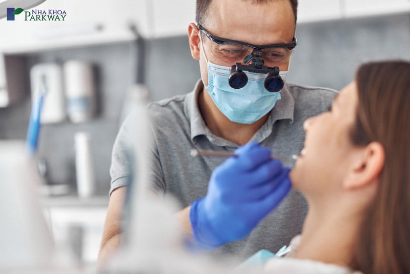 Bác sĩ đăng khám răng cho cô gái trước khi trồng răng implant