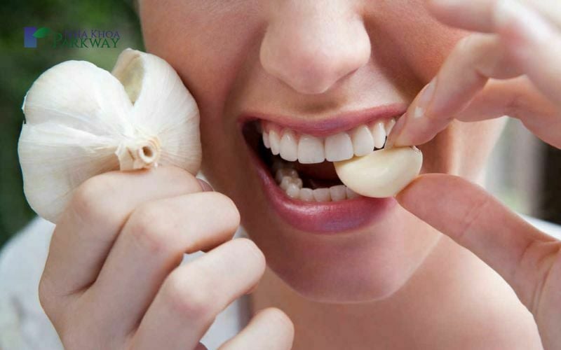 Hình ảnh người phụ nữ ăn tỏi để giảm đau răng