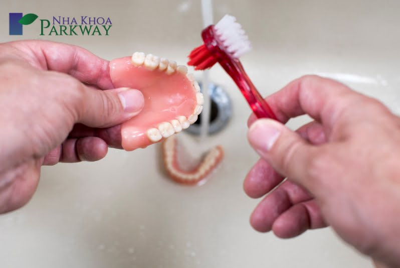 Dùng bàn chải để vệ sinh hàm răng giả