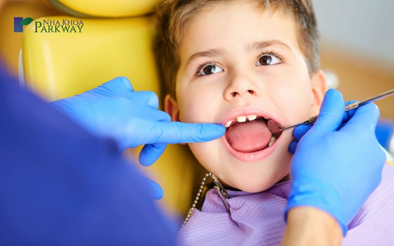 Nha sĩ dùng dụng cụ y khoa để kiểm tra hàm răng sữa của trẻ