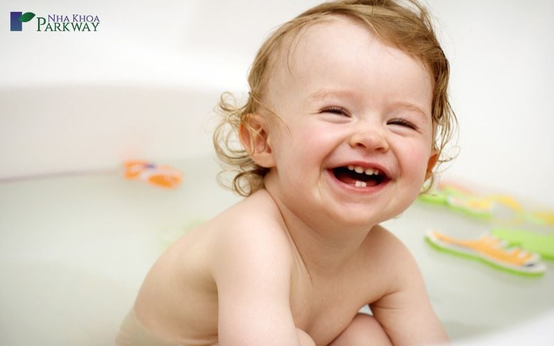 Hình ảnh đứa trẻ đang mỉm cười để lộ 2 hàm răng vừa mọc