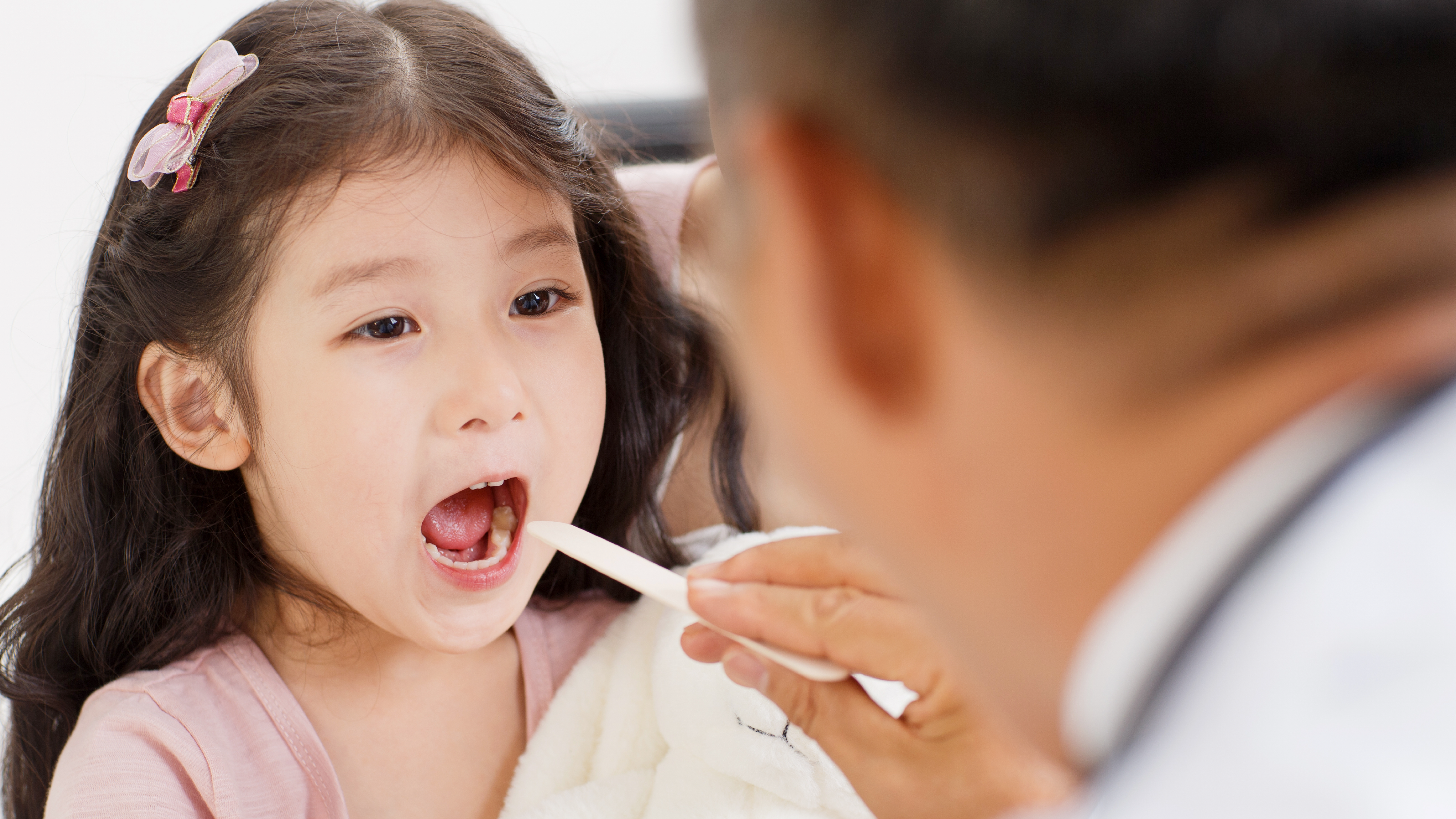 Bác sĩ dùng que để khám răng miệng trước khi thực hiện bọc mão cho răng sữa của em bé