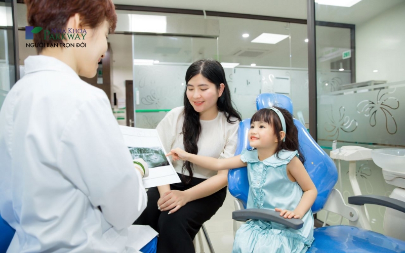 Bác sĩ trò chuyện và giải thích cho bé hiểu về tình trạng răng miệng thông qua ảnh chụp x-quang