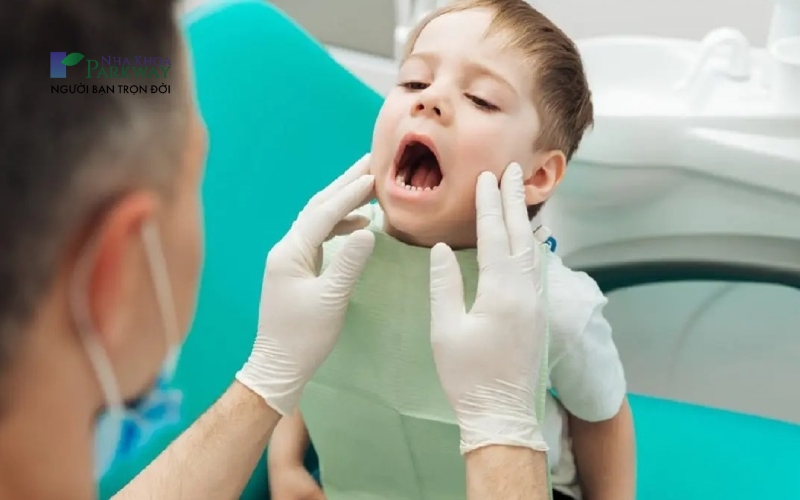 Bác sĩ nha khoa khám răng cho bé trai